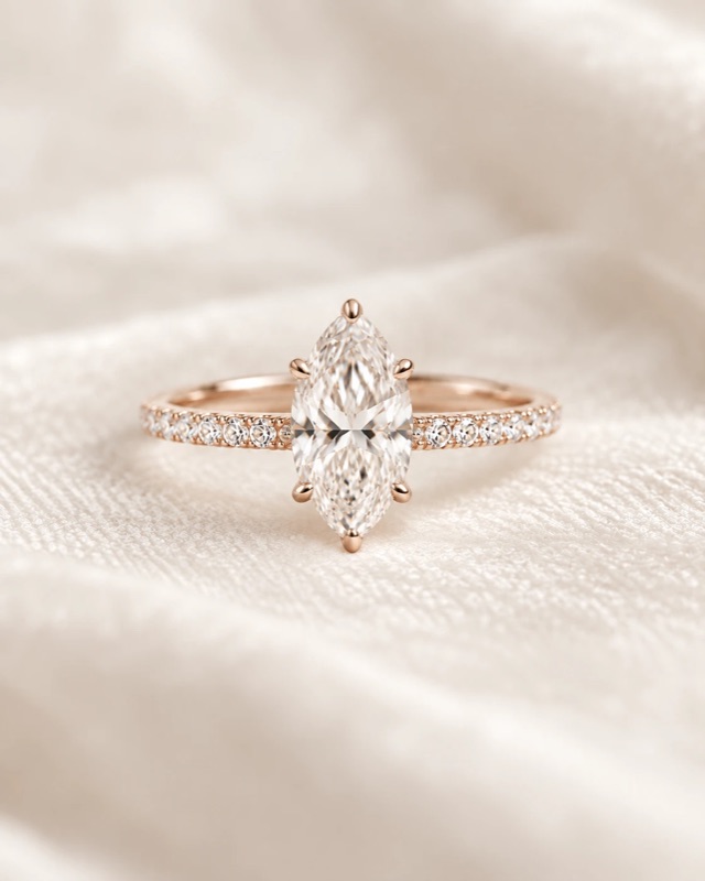 A marquise diamond engagement ring with a pavé band in rose gold