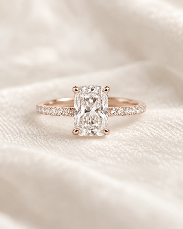 A radiant-cut diamond engagement ring with a pavé band in rose gold